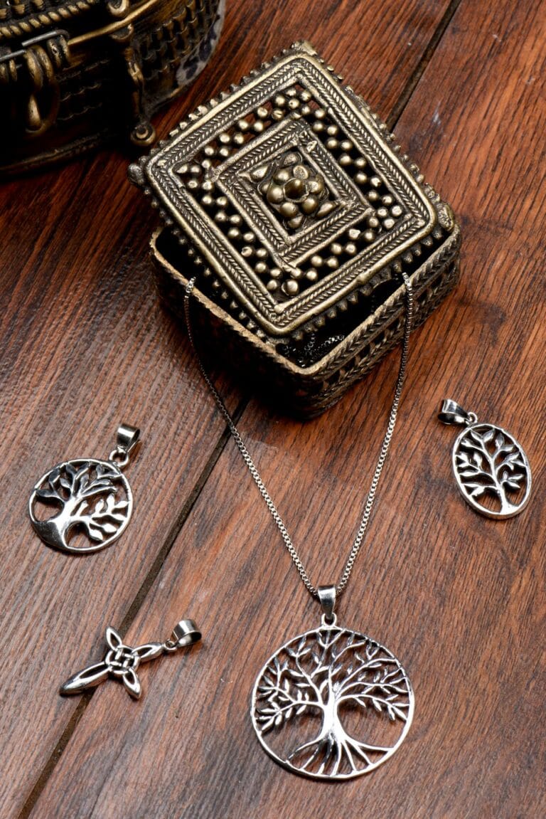Elegant Tree of Life pendants arranged artistically on a wooden table, showcasing intricate design.